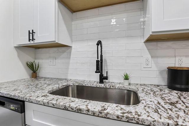 kitchen with dishwasher, sink, decorative backsplash, light stone counters, and white cabinetry