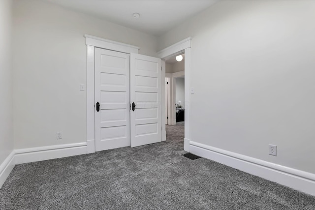 unfurnished bedroom with a closet and dark colored carpet