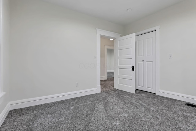 unfurnished bedroom featuring a closet and dark colored carpet