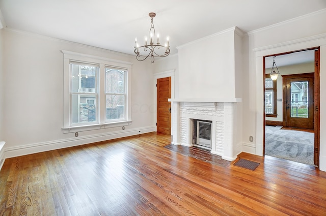 unfurnished living room featuring a notable chandelier, light hardwood / wood-style floors, crown molding, and a fireplace