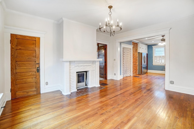 unfurnished living room with ceiling fan with notable chandelier, light hardwood / wood-style floors, and crown molding