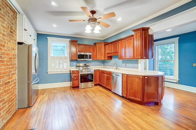 kitchen featuring a wealth of natural light, crown molding, appliances with stainless steel finishes, and light hardwood / wood-style flooring