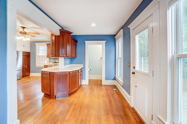 kitchen with light hardwood / wood-style floors, ceiling fan, and stainless steel stove