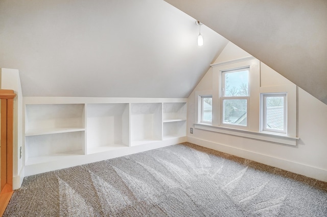 additional living space with carpet flooring, built in features, and vaulted ceiling