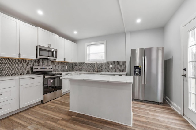 kitchen featuring white cabinetry, sink, a center island, appliances with stainless steel finishes, and light wood-type flooring