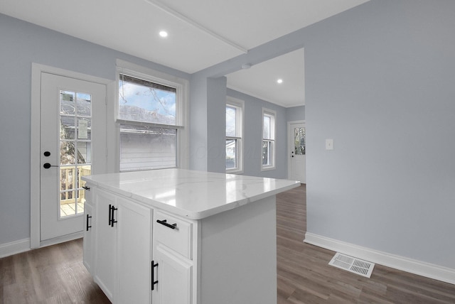 kitchen featuring white cabinets, light stone countertops, a kitchen island, and dark wood-type flooring