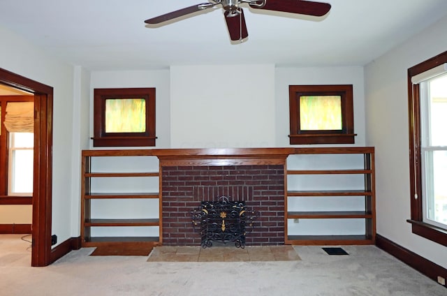 unfurnished living room featuring ceiling fan, a healthy amount of sunlight, a fireplace, and light carpet