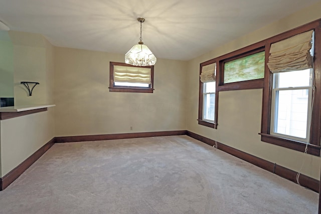 spare room with light carpet and a notable chandelier