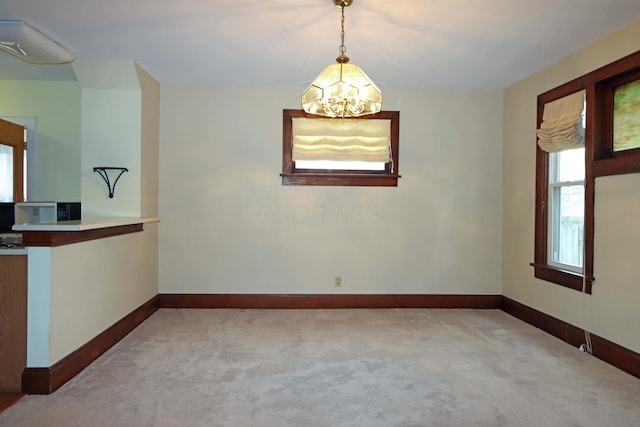 carpeted empty room featuring a notable chandelier