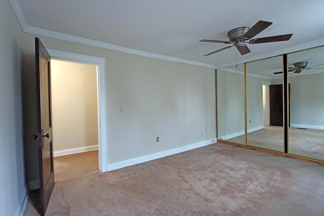 unfurnished bedroom featuring ceiling fan, light colored carpet, ornamental molding, and a closet