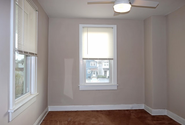 unfurnished room featuring ceiling fan and dark carpet