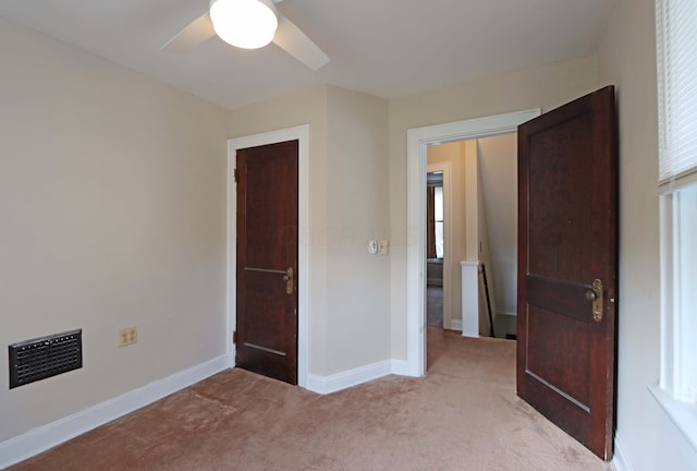 unfurnished bedroom with light carpet, multiple windows, and ceiling fan