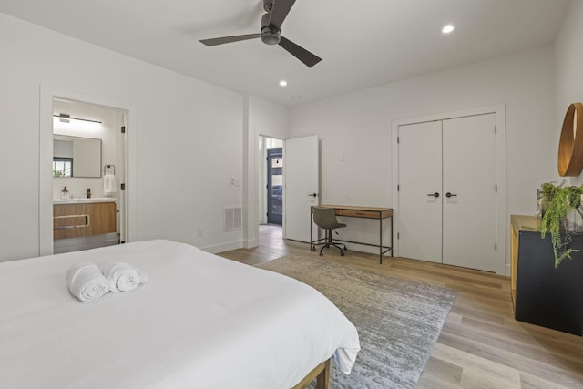 bedroom with ceiling fan, a closet, connected bathroom, and light hardwood / wood-style flooring