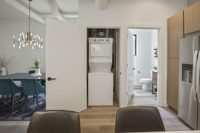 interior space featuring a notable chandelier, stacked washer / dryer, and light hardwood / wood-style flooring