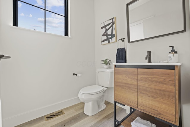 bathroom with hardwood / wood-style floors, vanity, and toilet