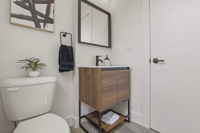 bathroom with hardwood / wood-style floors, vanity, and toilet