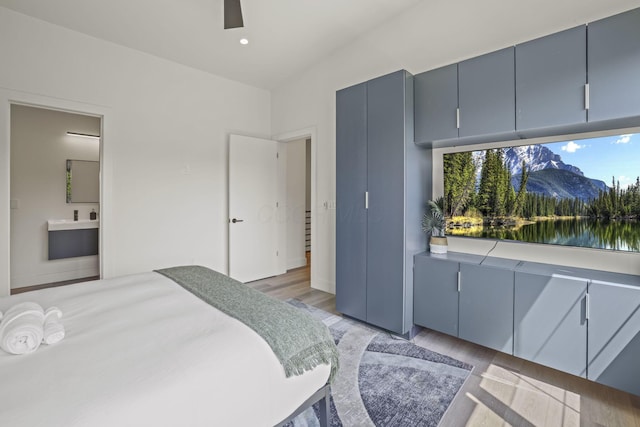 bedroom with ceiling fan, light wood-type flooring, and connected bathroom