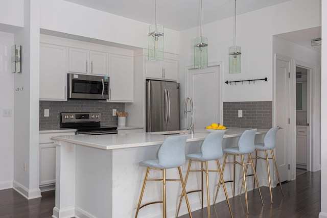 kitchen with white cabinetry, a kitchen breakfast bar, dark hardwood / wood-style flooring, pendant lighting, and stainless steel appliances