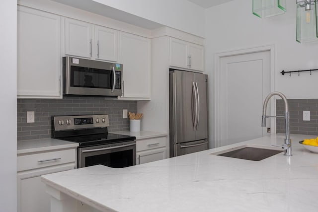 kitchen featuring white cabinetry, appliances with stainless steel finishes, sink, and light stone counters