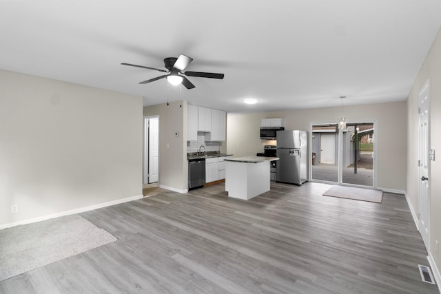 kitchen with white cabinets, light hardwood / wood-style flooring, appliances with stainless steel finishes, decorative light fixtures, and a kitchen island