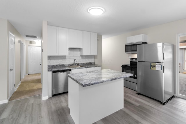 kitchen featuring white cabinets, sink, light hardwood / wood-style flooring, a kitchen island, and stainless steel appliances