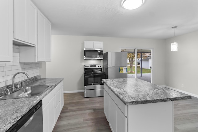 kitchen with appliances with stainless steel finishes, dark wood-type flooring, sink, white cabinets, and a kitchen island