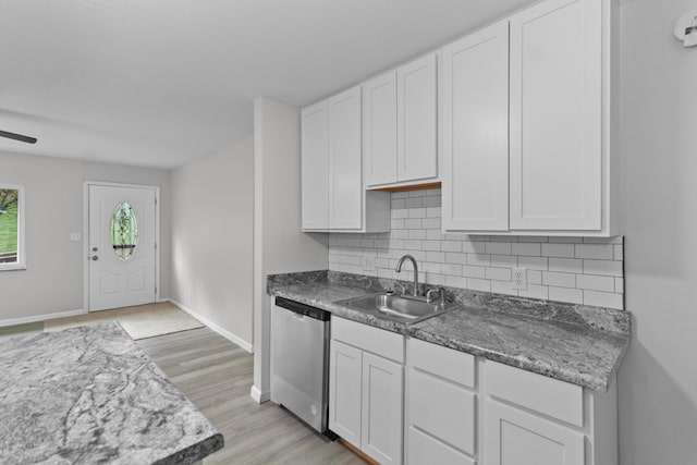 kitchen featuring tasteful backsplash, stainless steel dishwasher, sink, white cabinets, and light hardwood / wood-style floors