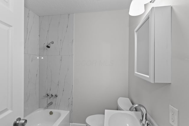 full bathroom featuring a textured ceiling, sink, tiled shower / bath combo, and toilet