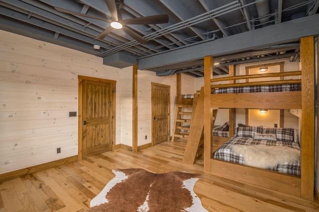 bedroom featuring hardwood / wood-style flooring, ceiling fan, and wood walls