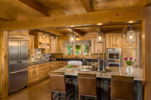 kitchen featuring a large island, sink, dark wood-type flooring, stainless steel appliances, and dark stone counters