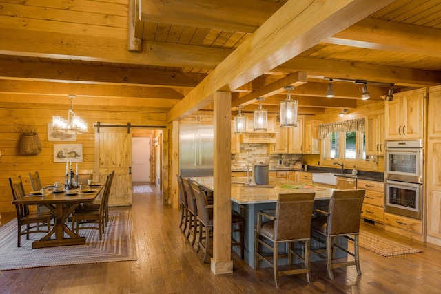 kitchen featuring decorative light fixtures, a barn door, stainless steel double oven, and wooden walls