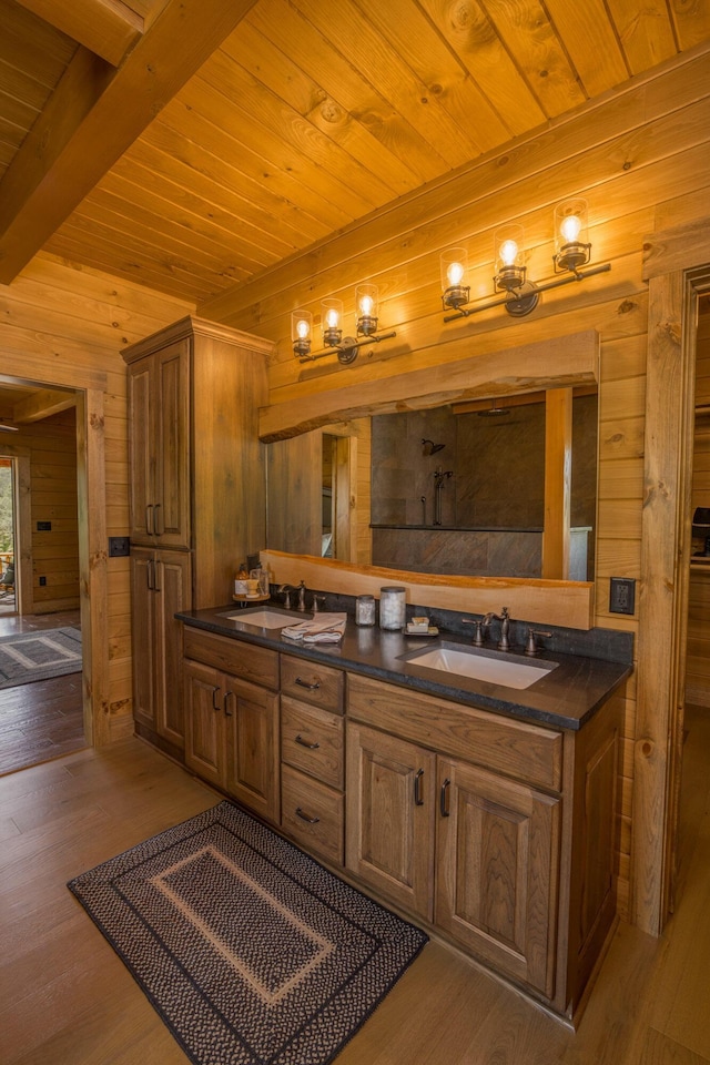 bathroom with hardwood / wood-style floors, vanity, beam ceiling, and wooden walls