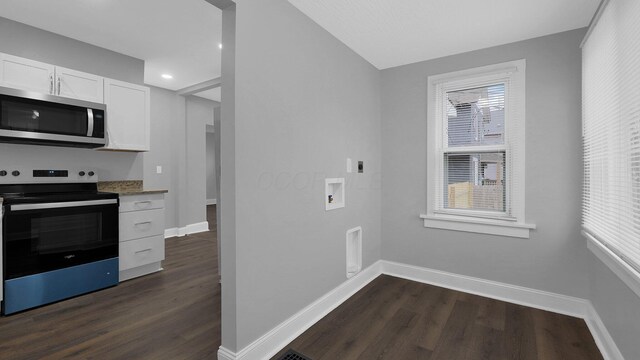 kitchen featuring light stone countertops, white cabinetry, dark wood-type flooring, and stainless steel appliances