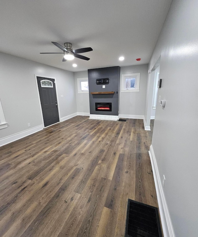 unfurnished living room with a fireplace, dark hardwood / wood-style flooring, and ceiling fan