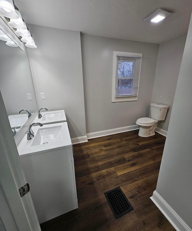 bathroom with wood-type flooring, vanity, and toilet