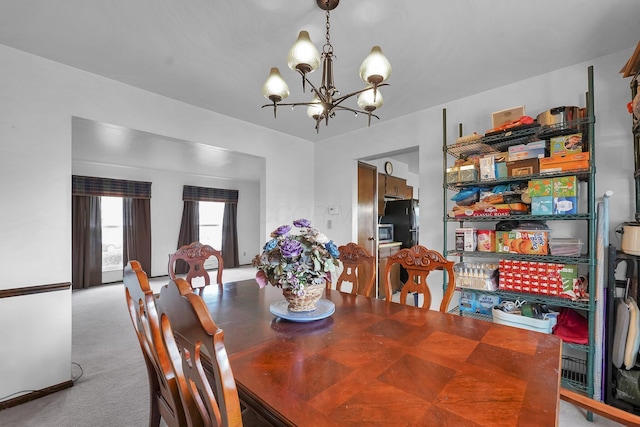 dining space with light colored carpet and a notable chandelier