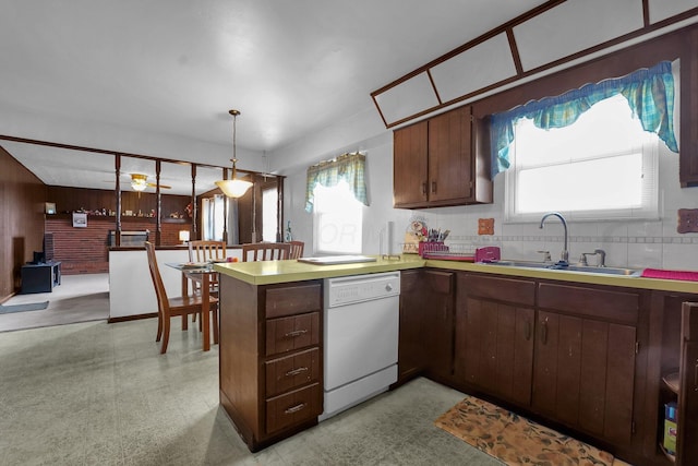 kitchen featuring dishwasher, sink, decorative backsplash, decorative light fixtures, and kitchen peninsula