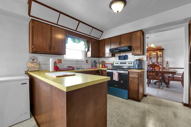 kitchen with kitchen peninsula, backsplash, electric stove, fridge, and lofted ceiling