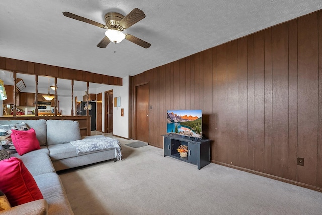 carpeted living room featuring ceiling fan, a textured ceiling, and wooden walls