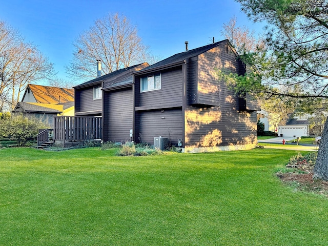 rear view of house with a lawn, a wooden deck, and central AC