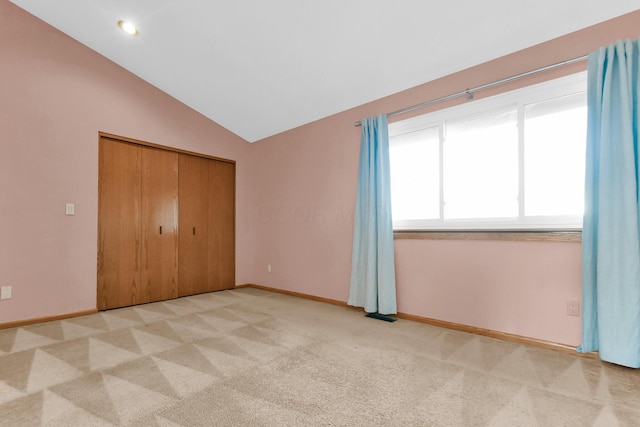 unfurnished bedroom featuring a closet, light colored carpet, and lofted ceiling