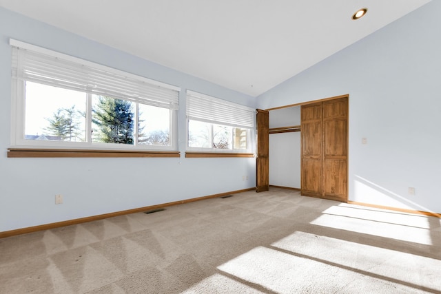 unfurnished bedroom featuring light colored carpet, vaulted ceiling, and a closet