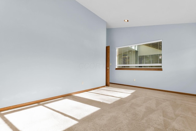 carpeted spare room with vaulted ceiling