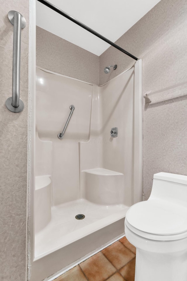 bathroom featuring tile patterned floors, toilet, and walk in shower