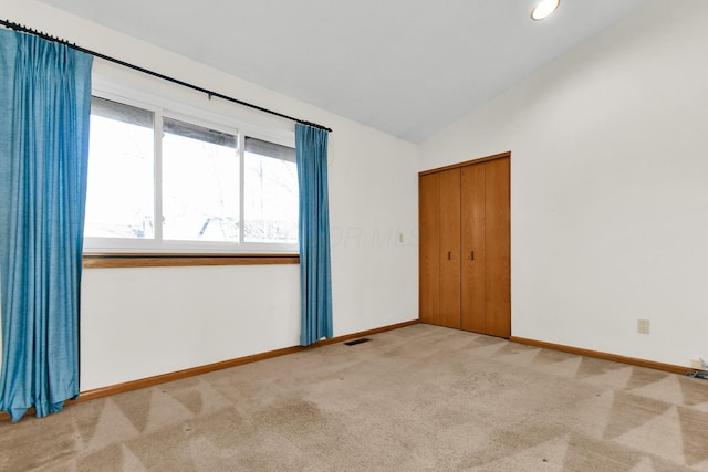 carpeted empty room featuring vaulted ceiling