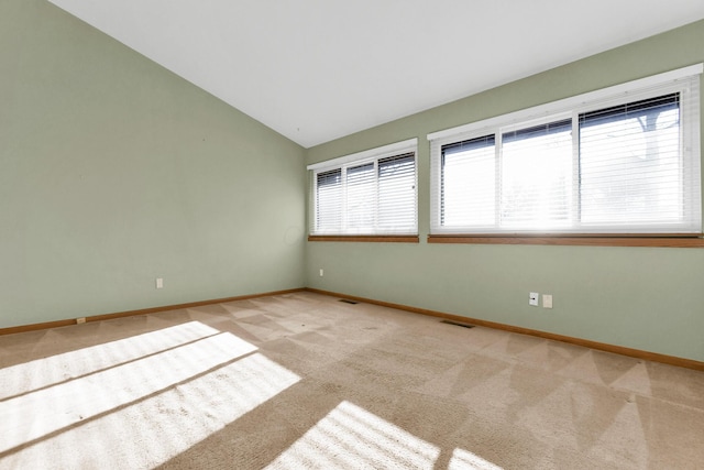 spare room featuring light colored carpet and vaulted ceiling