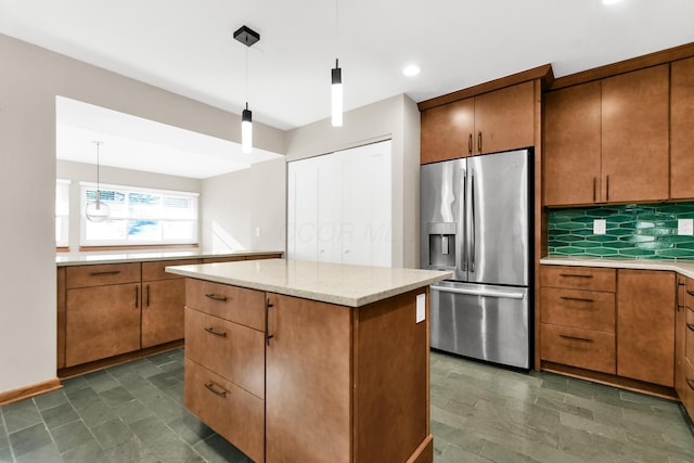 kitchen featuring decorative light fixtures, stainless steel fridge, a kitchen island, and backsplash