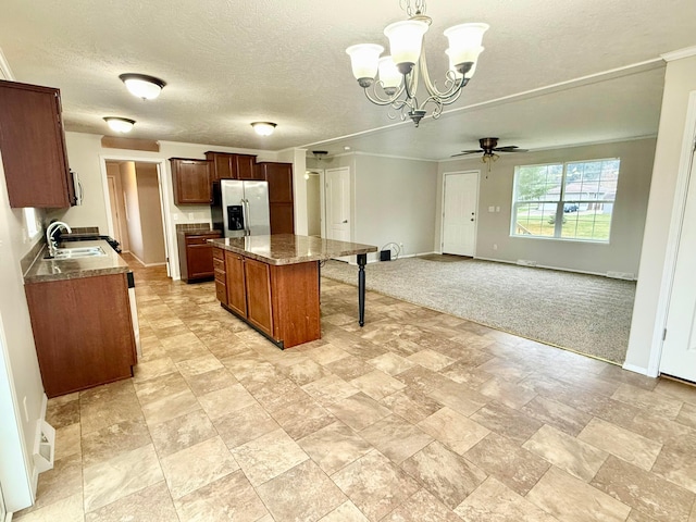 kitchen with pendant lighting, a center island, ceiling fan with notable chandelier, sink, and appliances with stainless steel finishes