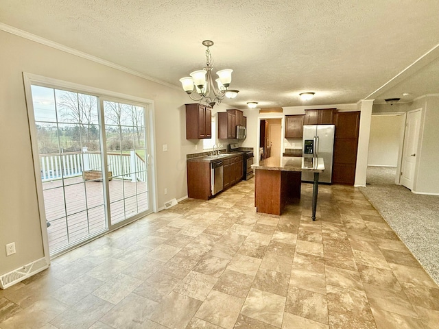 kitchen featuring a textured ceiling, stainless steel appliances, an inviting chandelier, a center island, and hanging light fixtures