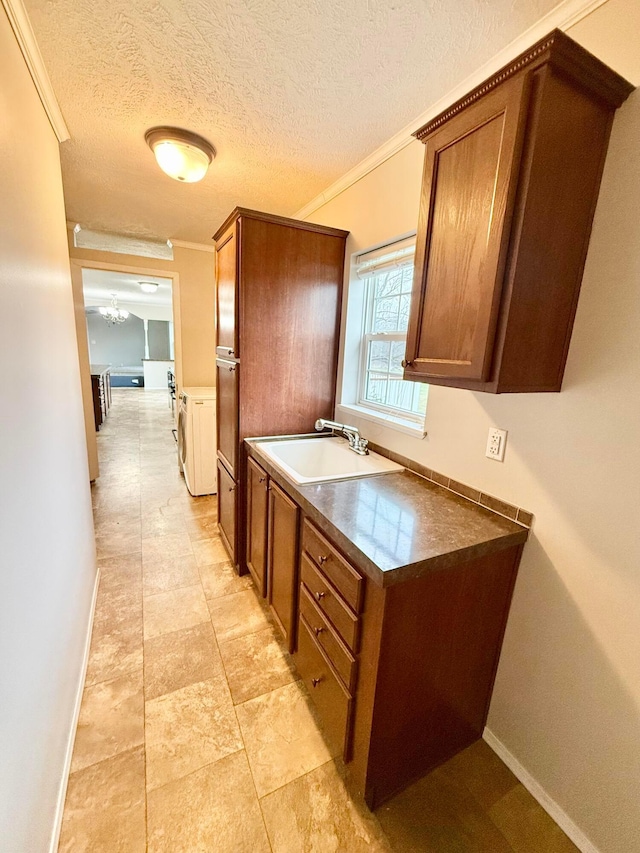 kitchen featuring a textured ceiling, crown molding, and sink